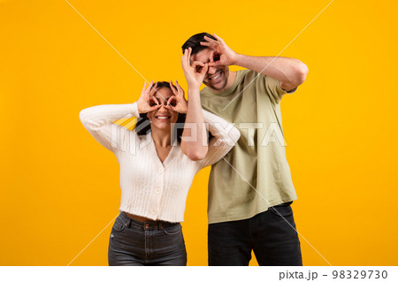 Happy millennial middle eastern male and female have fun doing glasses with hands, enjoy free time together Happy millennial middle eastern male and female have fun doing glasses with hands, enjoy free time together 98329730