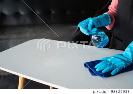 woman wearing Protective Gloves clean home. She using spray and cleaning on table. woman wearing Protective Gloves clean home. She using spray and cleaning on table. 98329983