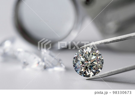 brilliant cut diamond held by tweezers on white background brilliant cut diamond held by tweezers on white background 98330673