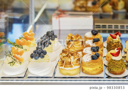Assortment of different desserts, cakes on cafe showcase. Various choice of sweets with fruits, berries 98330853