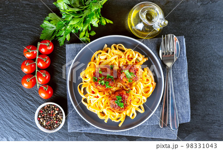 Homemade meatballs with tomato sauce and spices served in black pan on black slate background Homemade meatballs with tomato sauce and spices served in black pan on black slate background 98331043
