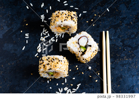 Sushi on a black table plate with wooden chopsticks. Eating japanese food at restaurant. Sushi on a black table plate with wooden chopsticks. Eating japanese food at restaurant. 98331997