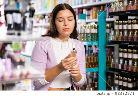 Cheerful beautiful woman choosing fragrance in beauty store Cheerful beautiful woman choosing fragrance in beauty store 98332971