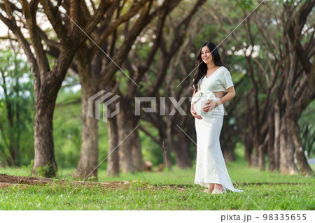 happy beautiful pregnant woman stroking her belly in the park 98335655