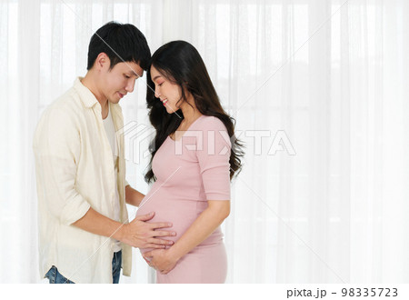 married couple is expecting baby. man embraces his pregnant wife on window background 98335723