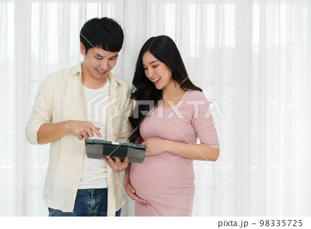 pregnant woman with her husband using digital tablet on window background 98335725