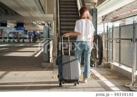woman traveler walking in International Airport or Subway platform. Tourist with luggage for Time to Travel, vacation and trip concepts 98338192