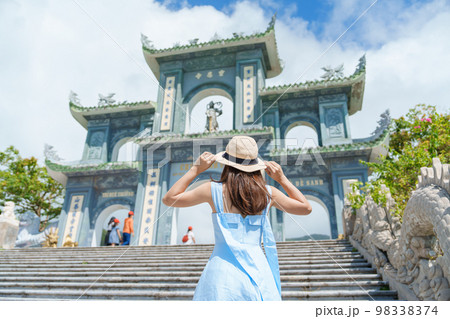 Woman traveler visiting at Linh Ung Pagoda temple, translation from Chinese character. Tourist with blue dress and hat traveling in Da Nang city. Vietnam and Southeast Asia travel concept 98338374