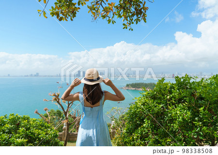 Woman traveler sightseeing Da Nang city view. Tourist with blue dress and hat traveling at Son Tra peninsula. Vietnam and Southeast Asia travel concept Woman traveler sightseeing Da Nang city view. Tourist with blue dress and hat traveling at Son Tra peninsula. Vietnam and Southeast Asia travel concept 98338508