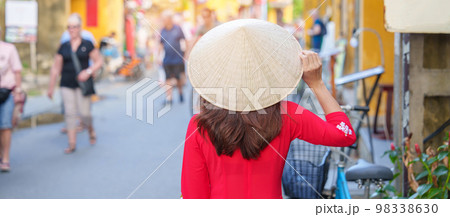 happy woman wearing Ao Dai Vietnamese dress, asian traveler sightseeing at Hoi An ancient town in central Vietnam. landmark and popular for tourist attractions. Vietnam and Southeast travel concept 98338630