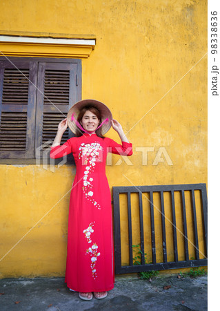 happy woman wearing Ao Dai Vietnamese dress and hat, traveler sightseeing at Hoi An ancient town in central Vietnam. landmark and popular for tourist attractions. Vietnam and Southeast travel concept 98338636