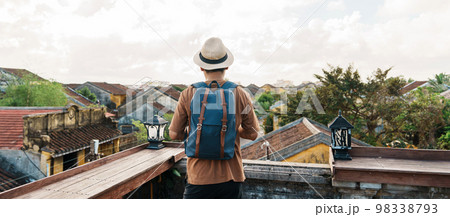 happy solo traveler traveling at Hoi An ancient town in Vietnam, man with backpack sightseeing view at rooftop.landmark and popular for tourist attractions. Vietnam and Southeast Asia travel concept happy solo traveler traveling at Hoi An ancient town in Vietnam, man with backpack sightseeing view at rooftop.landmark and popular for tourist attractions. Vietnam and Southeast Asia travel concept 98338793