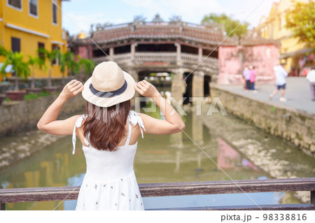 Woman traveler sightseeing at Japanese covered bridge or Cau temple in Hoi An ancient town, Vietnam. landmark and popular for tourist attractions. Vietnam and Southeast Asia travel concept 98338816