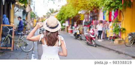 happy traveler sightseeing at Hoi An ancient town in central Vietnam, woman with dress and hat traveling. landmark and popular for tourist attractions. Vietnam and Southeast Asia travel concept 98338819