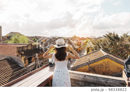 happy traveler traveling at Hoi An ancient town in Vietnam, woman with dress and hat sightseeing view at rooftop.landmark and popular for tourist attractions. Vietnam and Southeast Asia travel concept happy traveler traveling at Hoi An ancient town in Vietnam, woman with dress and hat sightseeing view at rooftop.landmark and popular for tourist attractions. Vietnam and Southeast Asia travel concept 98338822