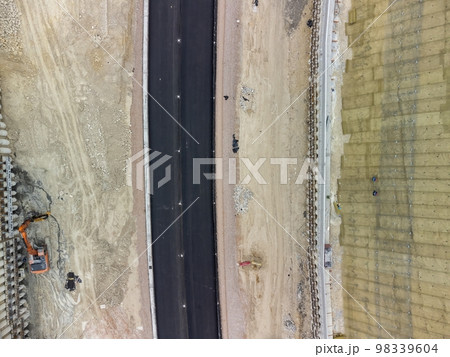 Mountain road constraction. Workers reinforce the slope over the new road. Road construction in progress on slope nature canyon. Infrastructure development and logistics. Aerial drone shot 98339604