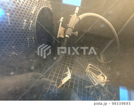 Shot blasting. Shot blasting of model printed on 3D printer from polyamide powder. A worker in sealed rubber gloves cleans the object by shot blasting in a shot blasting chamber. Industrial machine 98339693