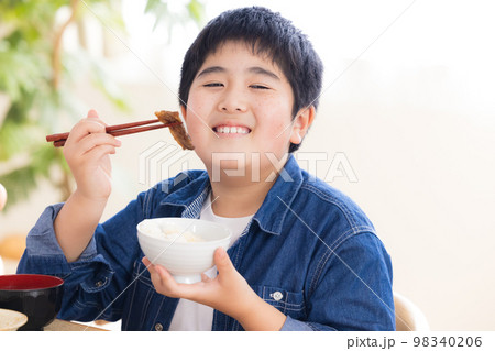 ファミリー　食事　お肉を食べる男の子 98340206