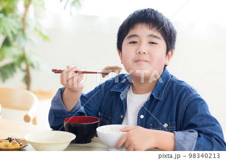 ファミリー　食事　お肉を食べる男の子 98340213