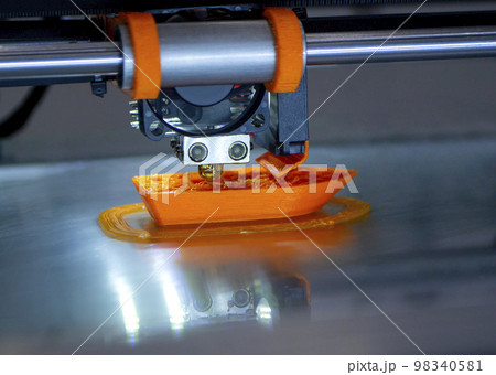 3d printer printing a model close-up. The process of printing a model on a 3D printer made of orange plastic. 3D printer working close up 98340581