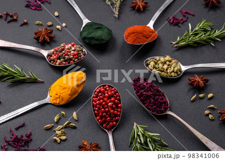Variation of spices in metal spoons paprika, turmeric, cardamom, a mixture of allspice 98341006