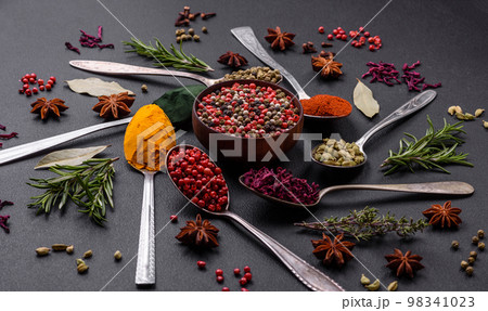 Variation of spices in metal spoons paprika, turmeric, cardamom, a mixture of allspice 98341023