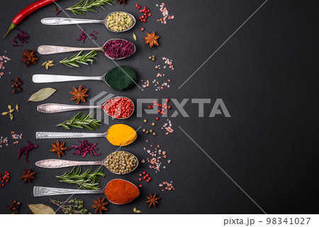 Variation of spices in metal spoons paprika, turmeric, cardamom, a mixture of allspice 98341027