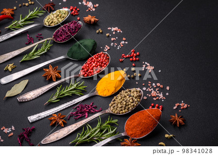 Variation of spices in metal spoons paprika, turmeric, cardamom, a mixture of allspice 98341028