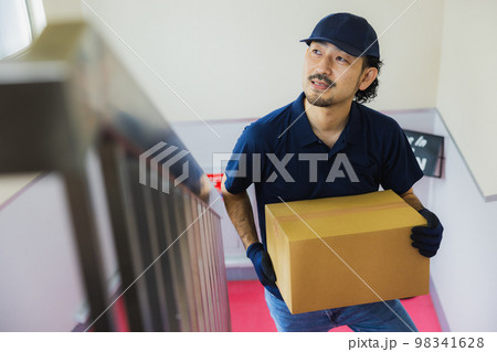 段ボールを持って階段を登る男性 98341628