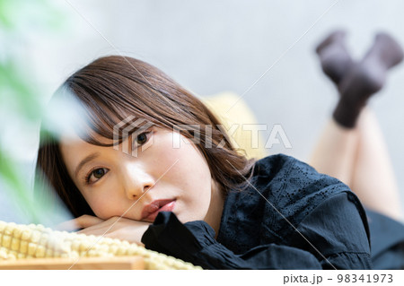 ソファーに寝転んでくつろぐ若い女性 ソファーに寝転んでくつろぐ若い女性 98341973