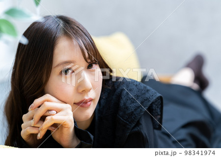 ソファーに寝転んでくつろぐ若い女性 ソファーに寝転んでくつろぐ若い女性 98341974