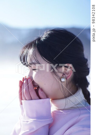 冬景色のなか白い息をはく女性 98342108