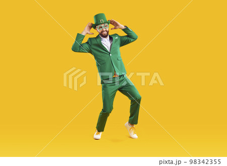 Happy funny guy in green suit and leprechaun hat having fun on Saint Patrick's Day 98342355