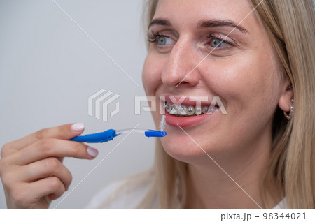 Caucasian woman cleaning her teeth with braces using a brush.  98344021