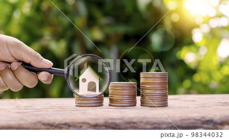 A magnifying glass and a model house on a pile of coins Savings concepts and financial plans for housing investments. A magnifying glass and a model house on a pile of coins Savings concepts and financial plans for housing investments. 98344032