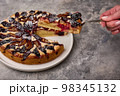Woman hand holds shoulder blade with piece of plum tart or pie, selective focus 98345132