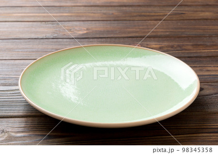 Perspective view of empty green plate on wooden background. Empty space for your design Perspective view of empty green plate on wooden background. Empty space for your design 98345358