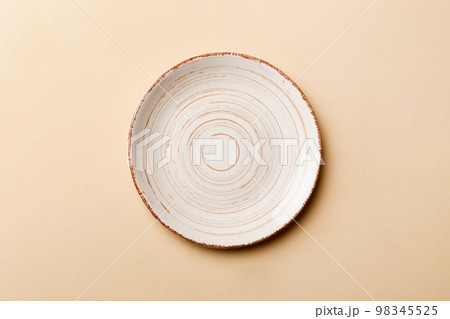 Top view of isolated of colored background empty round beige plate for food. Empty dish with space for your design 98345525