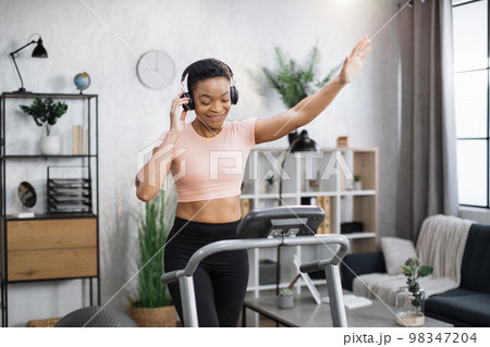 African american women with short curly hair in sports clothes and sneakers, listening music 98347204