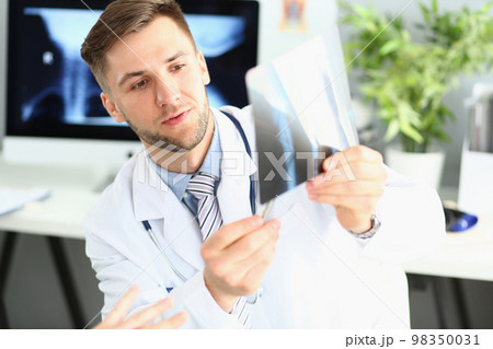 Male doctor examines x-ray of leg and arm in clinic 98350031