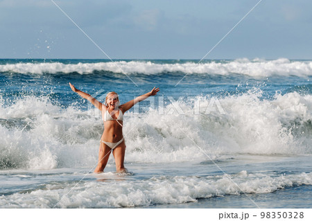 A girl with wet hair happily swims on the waves in the Atlantic Ocean.Tenerife.Spain A girl with wet hair happily swims on the waves in the Atlantic Ocean.Tenerife.Spain 98350328