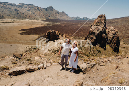 A married couple is standing in the crater of the Teide volcano. Desert landscape in Tenerife. Teide National Park. Tenerife, Spain A married couple is standing in the crater of the Teide volcano. Desert landscape in Tenerife. Teide National Park. Tenerife, Spain 98350348