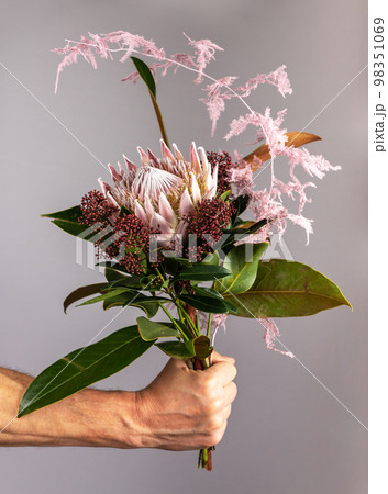 Flower bunch in men hand, spring romantic gift. Gentle gorgeous modern bouquet, posy of blossomed blooms, floral plants, leaf. High quality photo 98351069