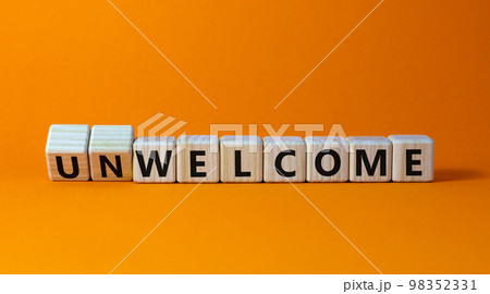 Welcome or unwelcome symbol. Turned wooden cubes and changed the word unwelcome to welcome. Beautiful orange table, orange background. Welcome or unwelcome and business concept. Copy space. Welcome or unwelcome symbol. Turned wooden cubes and changed the word unwelcome to welcome. Beautiful orange table, orange background. Welcome or unwelcome and business concept. Copy space. 98352331