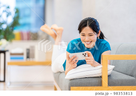 ソファーでスマホを操作する若い女性 98353813