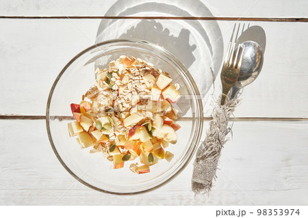Fitness nutrition, for a slim figure. Close-up of a healthy fruit salad in a glass bowl with slices of apple, banana with pumpkin seeds and oatmeal. High quality photo 98353974