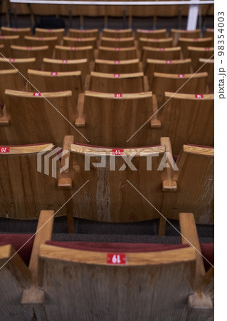 Chairs in a row for the audience. The concept of the cultural environment. Wooden and symmetrical . Empty seats. High quality photo Chairs in a row for the audience. The concept of the cultural environment. Wooden and symmetrical . Empty seats. High quality photo 98354003