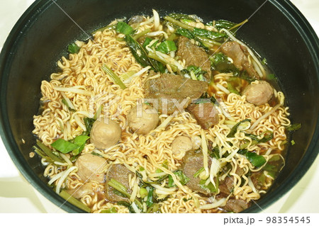 boiled instant noodles braised beef and meatball in black herb soup on electric cooking pot boiled instant noodles braised beef and meatball in black herb soup on electric cooking pot 98354545
