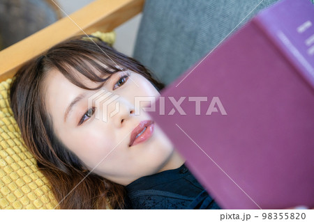 ソファで寝転んで読書する女性 ソファで寝転んで読書する女性 98355820