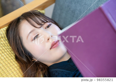 ソファで寝転んで読書する女性 ソファで寝転んで読書する女性 98355821